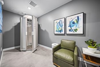 A room with a chair, a table, and two paintings on the wall.